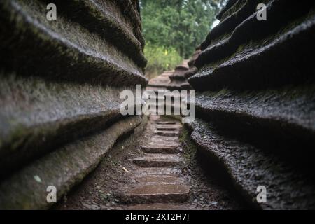 Stretto sentiero in pietra che si snoda attraverso formazioni rocciose che conducono verso l'alto in un ambiente naturale isolato Foto Stock