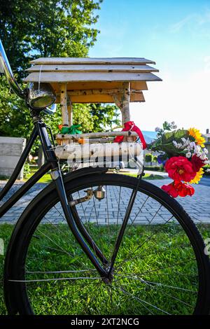 Bicicletta nera in stile retrò parcheggiata in una giornata di sole con una birdhouse e un bouquet colorato. Foto Stock