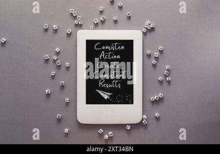 Una tavoletta bianca con le parole azione conseguenza crea risultati costanti scritti su di essa. Il tablet è circondato da una pila di cubi bianchi Foto Stock