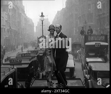 Una coppia che danzava il Charleston sulla cima di un'auto che percorreva una London Street, 1926. Da "Time to Remember 1926 - Short Sharp Shower" ( Reel 4); documentario sul 1926 - General Strike, International Politics, Dancing, Weather and record feats. Foto Stock