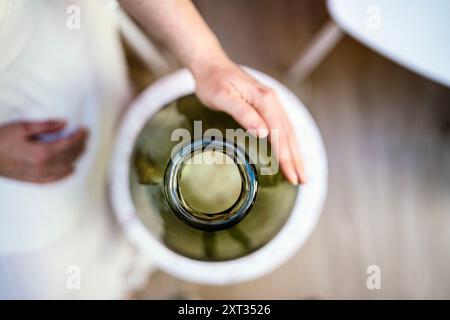 Donna mani su vaso in vetro verde scuro, Portogallo Foto Stock
