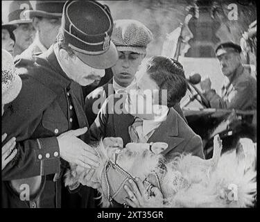 Scena del film "il marito obbligatorio": Monty Banks Holding a Dog That He Run Over, 1920 "...la Francia dello sceneggiatore era una delle auto costose guidate da cani gay francesi come Monty Banks, che era italiano di origine comunque. Correndo sopra animali domestici, e/o bambini, la trama è stata condotta nei canali appropriati, con introduzioni tra coppie sposate, che hanno messo in moto un altro tipo di tumulto". Da Time to Remember - Came the Dawn, 1925 (Reel 3); dai un'occhiata all'industria cinematografica britannica degli anni '1920 - clip di grandi film muti e notiziari. Foto Stock