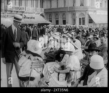 Scena del film "il marito obbligatorio": Folle di vacanzieri seduti nei caffè all'aperto degli anni '1920 "I visitatori di Deauville negli anni Venti potrebbero aver capito che era un posto piuttosto sfarzoso e rispettabile. AHA, ma non proprio la Deauville del paravento d'argento. Da Time to Remember - Came the Dawn, 1925 (Reel 3); dai un'occhiata all'industria cinematografica britannica degli anni '1920 - clip di grandi film muti e notiziari. Foto Stock