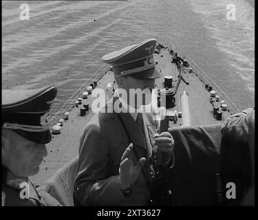 Adolf Hitler, il leader tedesco, a bordo di una nave da guerra della Marina italiana in una revisione navale nel Golfo di Napoli, 1937. "Sul ponte di una nave da battaglia nel Mediterraneo, il leader di tutti i tedeschi è intrattenuto dal leader di tutti gli italiani, (e non intendiamo il re d'Italia). I ragazzi erano tutti lì insieme, ispezionando la flotta italiana e stimando la sua potenza di combattimento in caso ci fossero... problemi. Da Time to Remember - Sense of Values, 1937 (Reel 1); documentario sugli eventi del 1937, guerra in Estremo Oriente, costruire fino alla guerra in Europa. Foto Stock