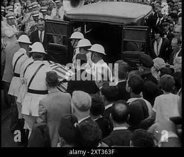 Soldati americani maschili nelle White Uniforms che prendono la Coffin di Anton Cermak, il sindaco di Chicago, fuori da un'auto e su un treno, 1933. STATI UNITI. Quando il presidente eletto [FDR] era in visita a Miami, in Florida, lì nel buio, qualcuno gli ha sparato. Il colpevole fu allontanato, ma anche se aveva mancato la sua mira, aveva trovato un bersaglio. Il sindaco di Miami, Cermak. Quindi, al posto di Franklin Roosevelt, il sindaco Cermak ha perso la vita. Si dice che prima di morire, una delle ultime cose che disse fu: "Sono contento che sia stato io". Da "Time to Remember - Around the Corner", (Reel 4); diario Foto Stock