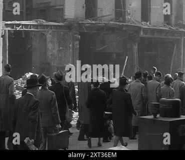 La folla che guarda gli edifici bombardati, 1940. La Gran Bretagna durante la seconda guerra mondiale: Il Blitz. Ogni notte, a qualsiasi ora, estate 1940. Fuoco e fiamme, morte e distruzione... qualsiasi mattina dopo a Londra... o è Coventry, Bristol, Portsmouth? Liverpool, Belfast, Birmingham? Plymouth o Glasgow?...eppure, con il caos di ogni alba, è meraviglioso come sopravviva l'abitudine. E' difficile uccidere la vita normale di una grande citta', difficile uccidere l'abitudine di andare al lavoro al mattino. Ma quale infamiliarità si può trovare nel vostro viaggio troppo familiare. Buchi dove non c'erano buchi ieri, niente case dove erano ieri Foto Stock