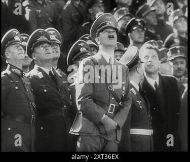 Adolf Hitler, il leader tedesco che guarda verso l'alto e guarda un volo passato di aeroplani con altri membri dell'alto comando nazista e ufficiali tedeschi, 1939. Da "Time to Remember - The Reluctant Warriors", 1939 (Reel 1); documentario sugli eventi del 1939 - i preparativi per la guerra e poi scoppiano le ostilità. Foto Stock