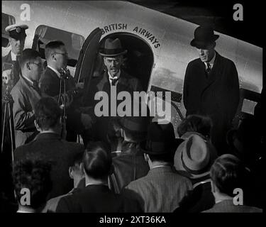 Il primo ministro britannico, Neville Chamberlain, in piedi alla porta di un aeroplano Lockheed accanto al ministro degli Esteri britannico Lord Halifax e parlando a una folla di giornalisti, 1938. Da "Time to Remember - Wind Up Week", 1938 (Reel 1); documentario sul 1938 - le persone diventano consapevoli della crescente minaccia della guerra. Foto Stock