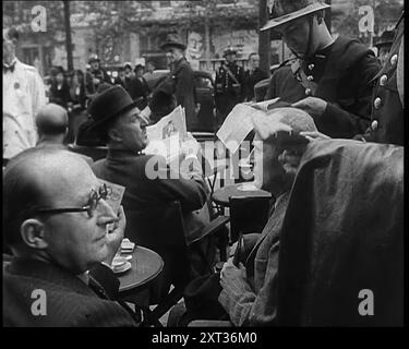 Polizia francese che controlla i documenti del popolo fuori da un caffè a Parigi, 1940. Seconda guerra mondiale. Parigi, maggio 1940. All'aspetto esteriore, Parigi come al solito. Ma interiormente, nervoso, preoccupato. Lungo gli Champs Elys&#xe9;es e i grands Boul&#xe9;vard, la polizia controlla i documenti di identità, perché la Francia è ora afflitta dalla paura dei Quinta editorialisti. Qualunque siano i trucchi di notizie dal fronte, è di confusione e ritirarsi. La città vive di voci, vere e false... così Parigi spera, e si ordina un altro ap&#xe9;ritif. Spera, e ci mette una bella faccia". Da "Time to Remember - Run Rabbit Run", 1940 ( Foto Stock