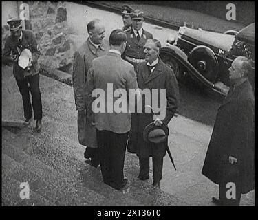 Adolf Hitler, il leader tedesco, stringendo la mano a Neville Chamberlain, il primo ministro britannico sui gradini del Berghof a Obersalzberg con un'auto sotto di loro e diversi funzionari maschi del governo tedesco presenti, 1938. Da "Time to Remember - Wind Up Week", 1938 (Reel 1); documentario sul 1938 - le persone diventano consapevoli della crescente minaccia della guerra. Foto Stock