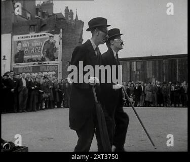 Two British Men in Suit and Hats Dancing in a Square with Men and Woman With Them with a Billboard Advertisement for the Nineteen Forty-Six Film, Mr Ace, Starring Sylvia Sidney and George Raft Behind Them, 1938. Da "Time to Remember - Wind Up Week", 1938 (Reel 1); documentario sul 1938 - le persone diventano consapevoli della crescente minaccia della guerra. Foto Stock