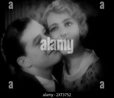 L'attore Ray Milland che abbraccia un attore britannico femminile, anni '1920 "A quei tempi [del cinema muto], la musica veniva suonata per mettere i giocatori nell'umore giusto...Ray Milland, conosciuto professionalmente sotto le luci allora come Spike". Da Time to Remember - Came the Dawn, 1925 (Reel 1); dai un'occhiata all'industria cinematografica britannica degli anni '1920 - clip di grandi film muti e notiziari. Foto Stock