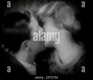 L'attore Ray Milland baciando un attore britannico donna, anni '1920 "A quei tempi [del cinema muto], la musica veniva suonata per mettere i giocatori nell'umore giusto...Ray Milland, conosciuto professionalmente sotto le luci allora come Spike". Da Time to Remember - Came the Dawn, 1925 (Reel 1); dai un'occhiata all'industria cinematografica britannica degli anni '1920 - clip di grandi film muti e notiziari. Foto Stock
