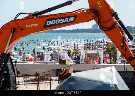 Voller Sommerstrand in Scharbeutz Das Bild zeigt einen vollen Strand in Scharbeutz an der heißen an einem sonnigen Ostseeküste Sommertag. Der Strand ist dicht besetzt mit Strandkörben, bunten Sonnenschirmen und zahlreichen Badegästen, die das warme Wetter genießen. Im Wasser tummeln sich Menschen, die schwimmen oder einfach im seichten Wasser stehen. Im Vordergrund ist ein Bagger zu sehen. An vielen Orten in Deutschland könnte es heute der bislang heißeste Tag des Jahres werden. Scharbeutz Schleswig-Holstein Deutschland *** Spiaggia estiva completa a Scharbeutz l'immagine mostra una spiaggia piena a Scha Foto Stock