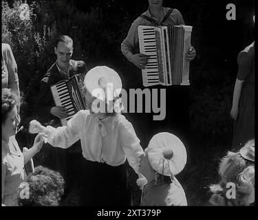 A Group of British Girls Dancing as Two British Men Play Accordion Music, 1938. Da "Time to Remember - Wind Up Week", 1938 (Reel 1); documentario sul 1938 - le persone diventano consapevoli della crescente minaccia della guerra. Foto Stock