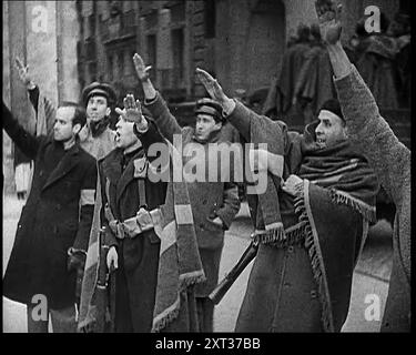 Uomini armati e civili che fanno saluti fascisti in una strada di Madrid, tutti vestiti con cappotti spessi e due con coperte drappeggiate intorno alle spalle, 1939. Da "Time to Remember - The Reluctant Warriors", 1939 (Reel 1); documentario sugli eventi del 1939 - i preparativi per la guerra e poi scoppiano le ostilità. Foto Stock