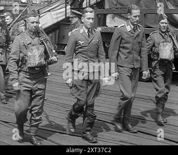 Due piloti tedeschi catturati scortati via, 1940. Seconda guerra mondiale. "...aviatori della "razza padronale" raccolti dal mare [dopo essere stati abbattuti al largo della costa inglese]". Da Time to Remember - Standing Alone, 1940 (Reel 3); film documentario sugli eventi dei mesi successivi del 1940. Foto Stock