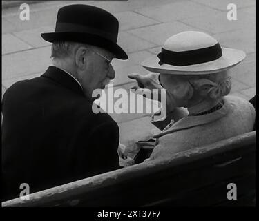 Vista posteriore di un uomo e di una donna anziani seduti su una panchina e che parlano, entrambi con cappelli e occhiali, 1938. Da "Time to Remember - Wind Up Week", 1938 (Reel 3); documentario sul 1938 - le persone diventano consapevoli della crescente minaccia della guerra. Foto Stock