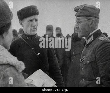 Due soldati russi che parlano con un prigioniero di guerra tedesco, 1941. Seconda guerra mondiale. L'operazione Barbarossa fu l'invasione dell'Unione Sovietica da parte della Germania nazista. Il vento sulle steppe non porta solo la risposta dei cannoni russi. Porta anche il freddo, l'inconfondibile respiro della sconfitta finale". Da "Time to Remember - Operation Barbarossa", 1941 (Reel 4); documentario sugli eventi del 1941, sul fronte orientale e a Pearl Harbour. Foto Stock