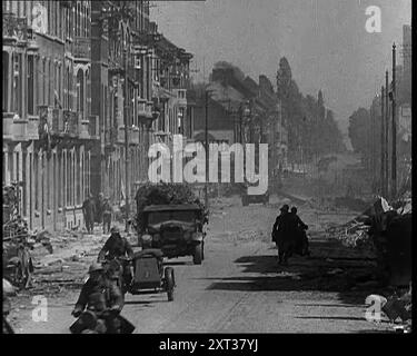 British Expeditionary Force in ritirata attraverso la città belga a bordo di veicoli, 1940. Seconda guerra mondiale. "Scendendo dal Belgio settentrionale si ritira la British Expeditionary Force, tornando indietro quasi alla stessa velocità di una volta corsa in avanti. Ma, sebbene superata, si tratta di una forza ancora una unità combattente, anche se per quanto tempo può rimanere tale è problematico”. Da "Time to Remember - Run Rabbit Run", 1940 ( Reel 3); film documentario sugli eventi dei primi mesi del 1940. Foto Stock