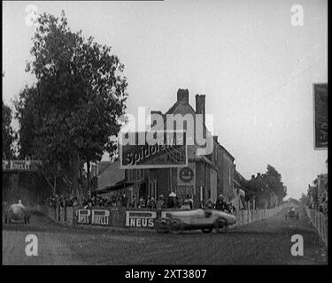 Un circuito da corsa come Racing Cars Drive by. Insegne su un edificio leggere: 'Spidoleine Huile' e 'Pirelli Pneus', 1924. Da "Time to Remember - A Trip to Europe", 1924 (Reel 3); uno sguardo alla vita politica e sociale in Europa e oltre nel 1924. Foto Stock