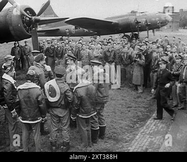 Un grande gruppo di piloti americani in piedi sotto un bombardiere. Diversi piloti stanno camminando verso l'aereo, 1943-1944. Da Time to Remember - Round the Clock, 1943 - 1944 ( Reel 1); documentario sugli eventi del 1943-1944, principalmente missioni di bombardamento in Europa. Foto Stock