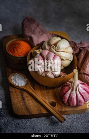 Una fotografia calda e invitante che mostra aglio fresco e spezie vivide include una ciotola di legno piena di spicchi d'aglio e un'altra con finissima spi arancione Foto Stock