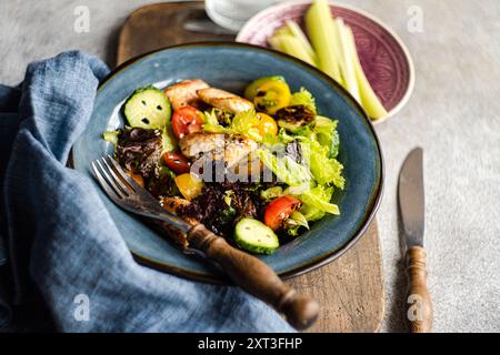 Dall'alto una sana insalata fatta in casa con pollo alla griglia, lattuga, pomodori ciliegini, cetrioli, peperoni, e semi di sesamo, serviti splendidamente Foto Stock