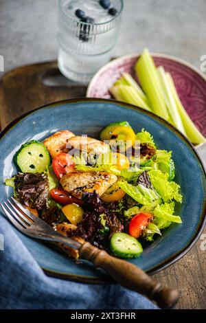 Vista dall'alto di un'insalata fresca fatta in casa con pomodori ciliegini, cetrioli, peperoni, lattuga, pezzi di pollo alla griglia, e cosparso di semi di sesamo Foto Stock