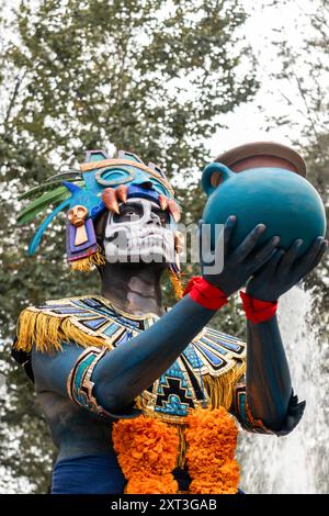 Una persona in un vivace costume Catrin con trucco del cranio e un grande vaso di ceramica celebra il giorno dei morti in Messico Foto Stock