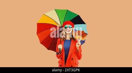 Abito in stile autunnale, bella giovane donna sorridente con foglie d'acero giallo e ombrello colorato con cappello rosso di berretto francese, cappotto su marrone st Foto Stock