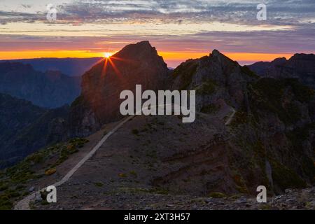 Accattivante vista del sole che sorge sopra il paesaggio montuoso di Madeira, illuminando il terreno accidentato e mettendo in evidenza un sentiero tortuoso Foto Stock