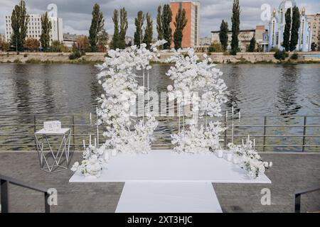 Elegante allestimento per matrimoni all'aperto con composizioni floreali bianche in riva all'acqua Foto Stock