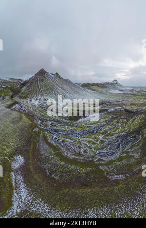 Una vista panoramica delle Green Highlands in Islanda, caratterizzata da vette innevate e lussureggianti vallate verdi sotto un cielo nuvoloso, questo spettacolare spettacolo paesaggistico Foto Stock