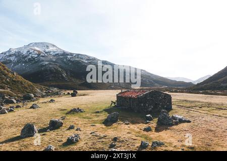 Un pittoresco rifugio in pietra accoccolato tra le vaste praterie aperte dei Monti Palencia, che mostrano un tranquillo mix di bellezza naturale e rustica Foto Stock