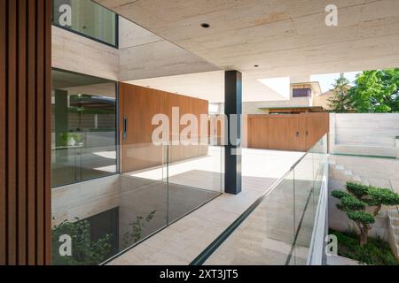 Immagine di una casa moderna con linee pulite, ringhiere di vetro e pannelli di legno la struttura presenta una miscela unica di pietra, vetro e legno, illustre Foto Stock