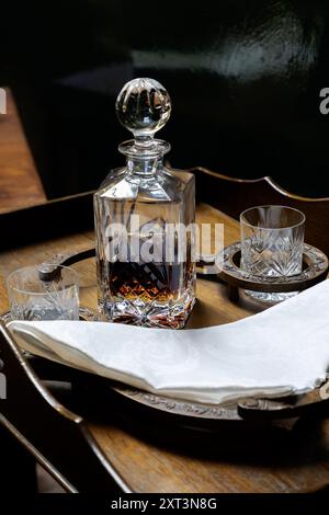 decanter e due bicchieri sono disposti su un piccolo tavolino Foto Stock