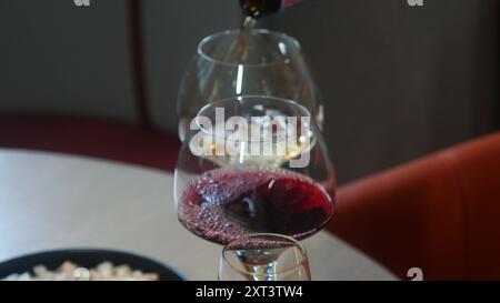 Due bicchieri di vino rosso versati in un ambiente accogliente, enfatizzando Foto Stock