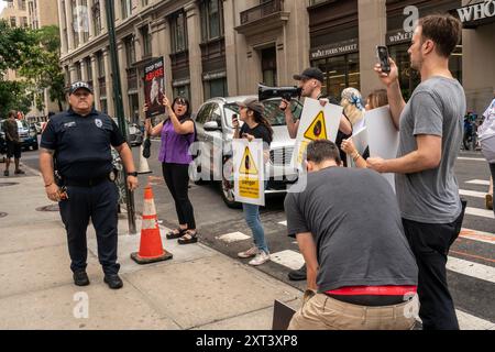 Membri del NYPD corral manifestanti per i diritti degli animali fuori dal negozio Crumbl a Chelsea a New York venerdì 9 agosto 2024 durante un'attivazione del marchio. I manifestanti si sono opposti alla catena dei biscotti che utilizza uova di galline tenute in presunte condizioni non sanitarie e abusive. (© Richard B. Levine) Foto Stock