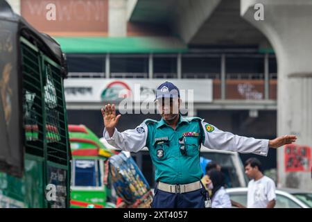 Un agente della polizia stradale bengalese dà istruzioni agli autisti dopo che la polizia ha annullato lo sciopero e ha ripreso le loro funzioni dopo un incontro con il governo provvisorio. La polizia del Bangladesh ha ripreso le pattuglie della capitale Dacca, ponendo fine a uno sciopero di una settimana che ha lasciato un vuoto di legge e ordine a seguito della brusca estromissione dell'ex Premier autocratico Sheikh Hasina. Foto Stock