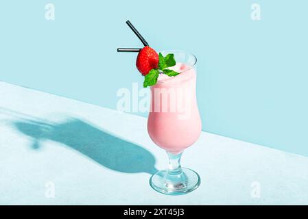 Bicchiere di frullato di fragole fresco, frullato con menta e fragola fresca su sfondo azzurro, ombra rigida, spazio per copiare. Cibo e bevande salutari Foto Stock
