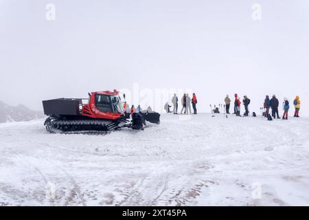 Elbrus, Russia - 1 agosto 2024: Trasporto di turisti attraverso un ghiacciaio in fusione con gatto delle nevi in una nuvola sulle pendici del Monte Elbrus Foto Stock