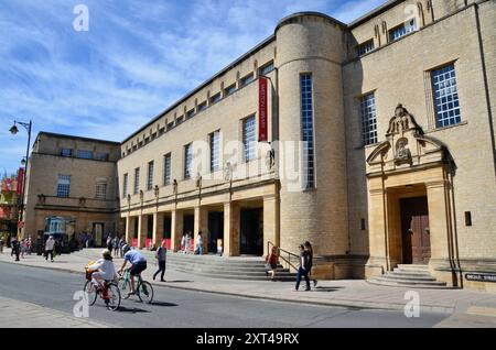 Due ciclisti passano davanti alla biblioteca weston Broad Street oxford inghilterra Regno Unito Foto Stock