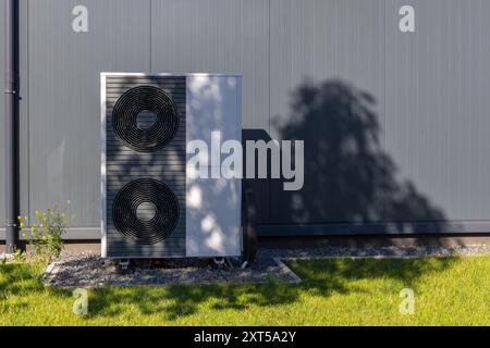 Moderna unità pompa di calore contro l'esterno dell'edificio grigio Foto Stock