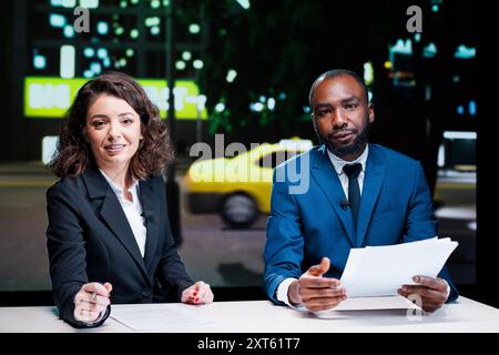 Diversi giornalisti che leggono i titoli negli studi di stampa, lavorano nell'industria televisiva per creare contenuti esclusivi. Team di giornalisti dal vivo che copre tutti gli argomenti importanti, il segmento dell'intrattenimento. Foto Stock