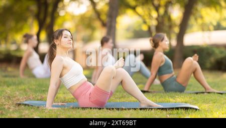 Lezione di yoga le ragazze eseguono hindolasana nel parco Foto Stock