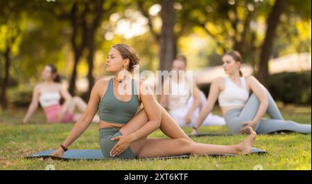 Lezione di yoga le ragazze eseguono wakrasana nel parco Foto Stock