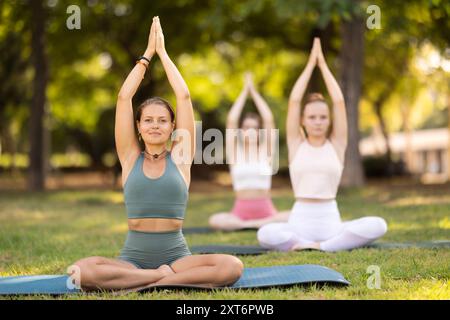 Lezione di yoga le ragazze eseguono padmasana nel parco Foto Stock