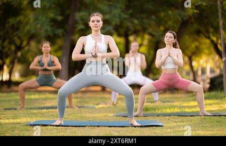 Lezione di yoga le ragazze eseguono utkata konasana nel parco Foto Stock