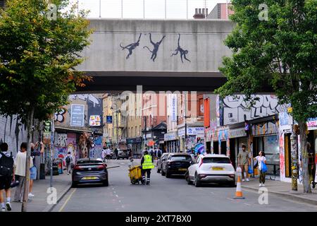 Una terza opera d'arte di Banksy appare per il terzo giorno consecutivo, questa volta a Brick Lane. Tre scimmie oscillanti sono apparse su un ponte ferroviario. Foto Stock